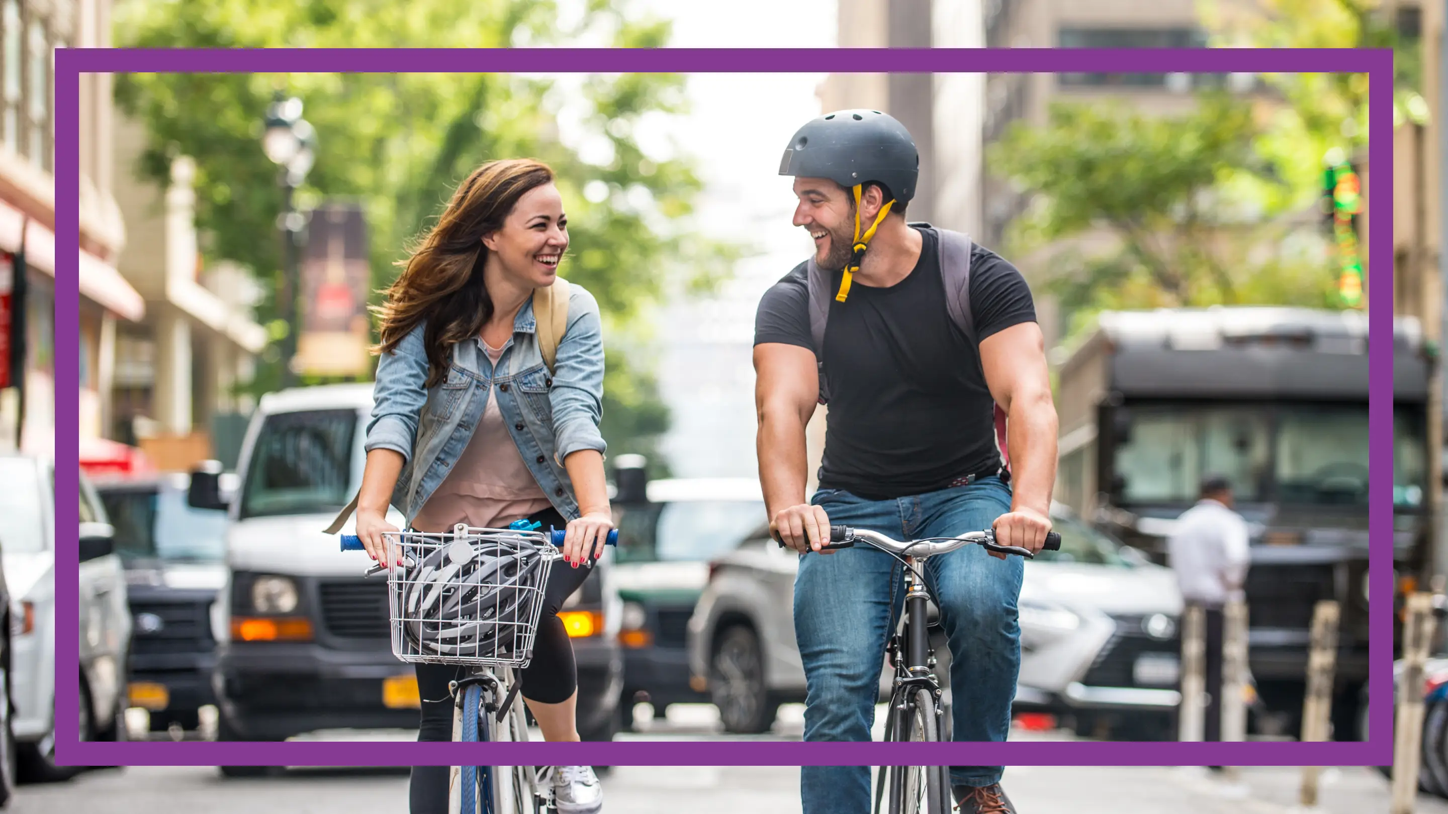 Mujer y hombre jóvenes andando en bicicleta por la calle de una ciudad.